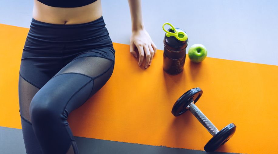 An image of a woman's legs sitting on a yoga mat, focusing on her leggings