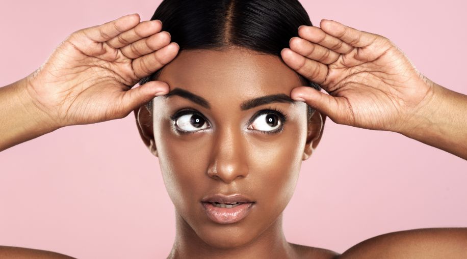 A Black woman holding her hands up by her face, showing off her eyebrows
